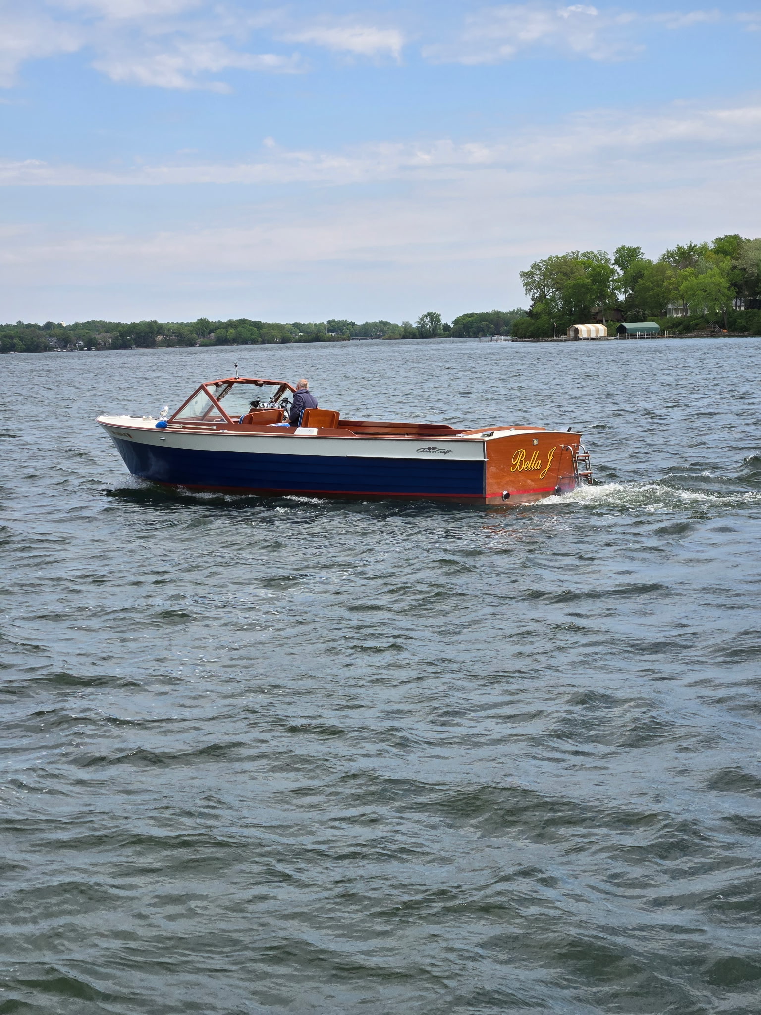 'Bella J' — a beautifully restored classic wooden boat cruising on a Minnesota lake.