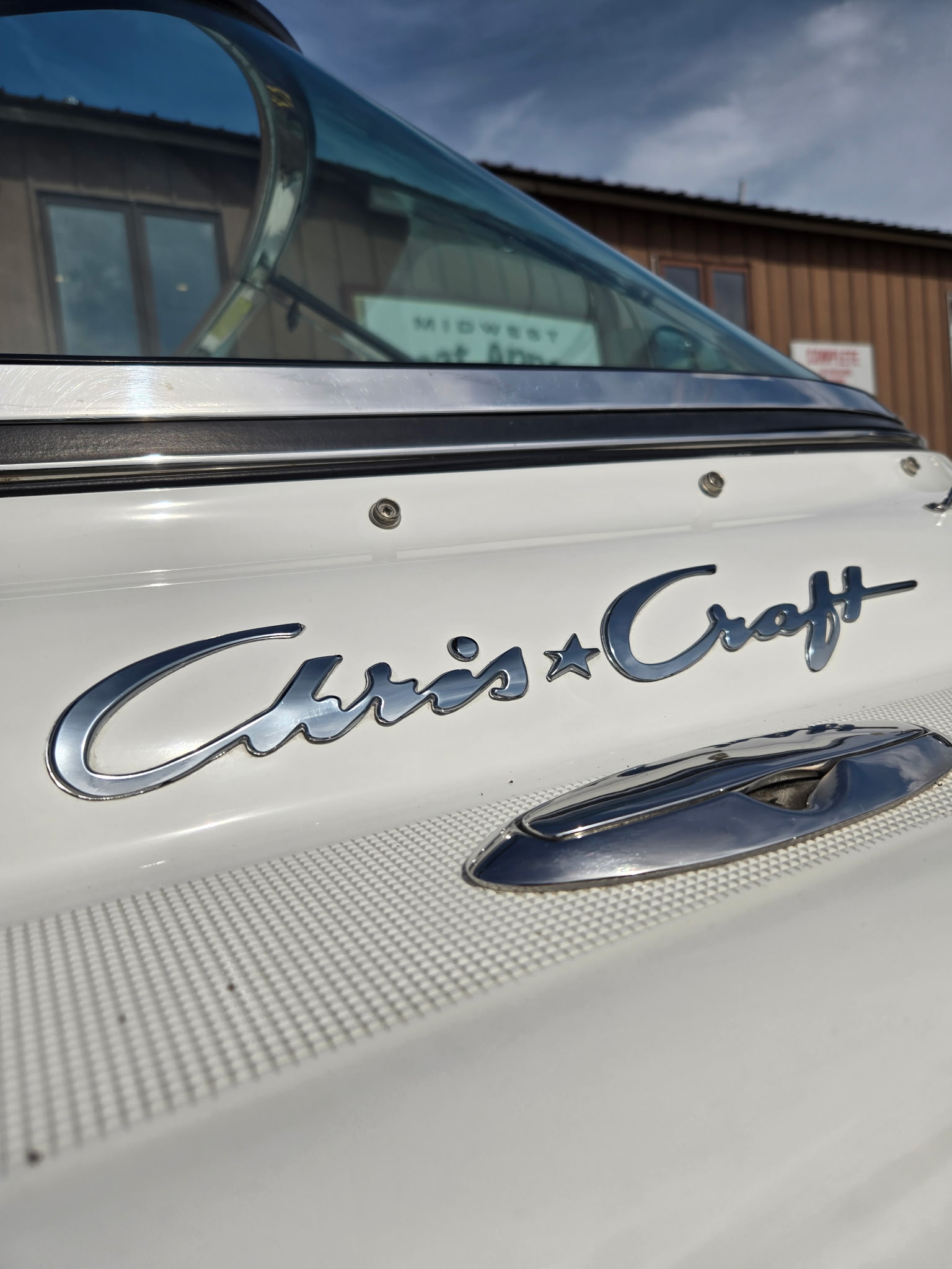 Chris-Craft badge, with Midwest Boat Appeal shop sign in background.