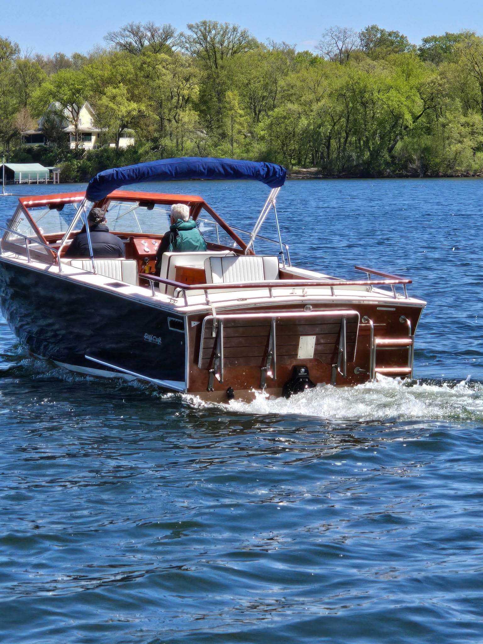 Classic wooden boat underway on a Minnesota lake, mahogany stern detail.