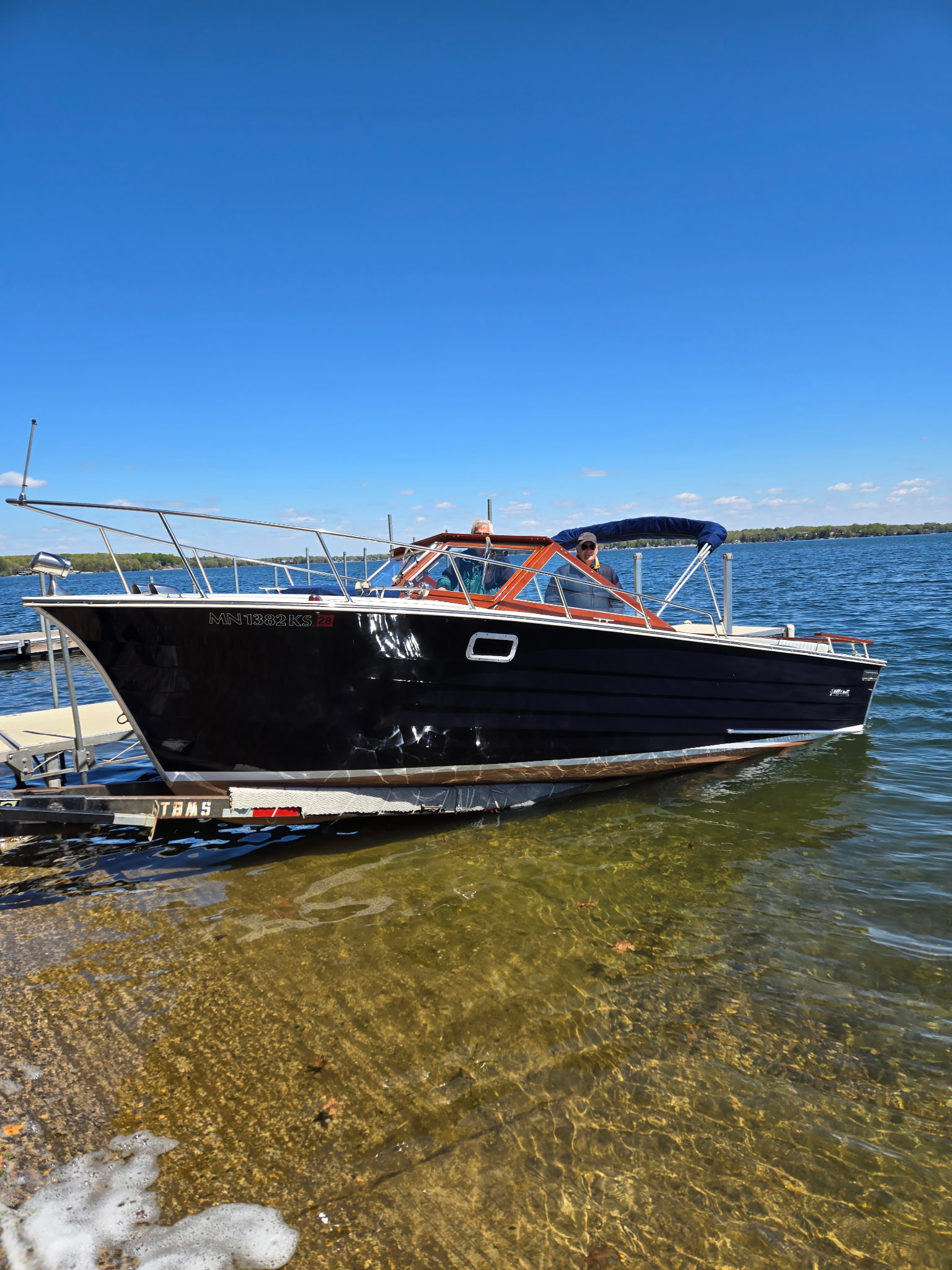 Classic wooden boat at a Minnesota launch on a brilliant blue-sky day.