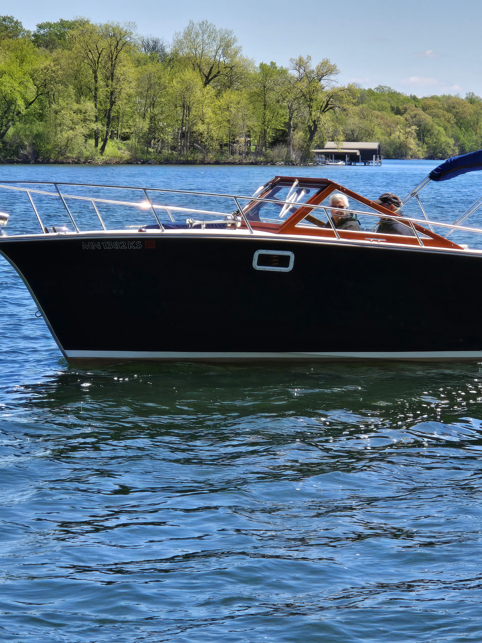 Classic wooden boat underway on a Minnesota lake, mahogany and chrome glowing.