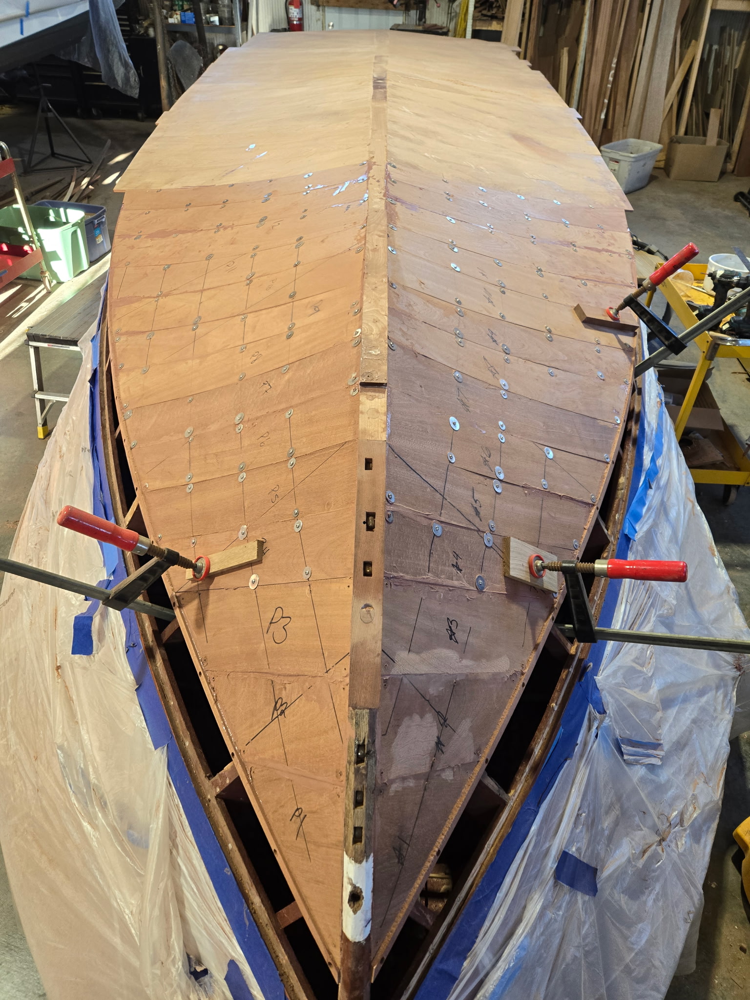 Boat bow being rebuilt with new mahogany planking in the shop.