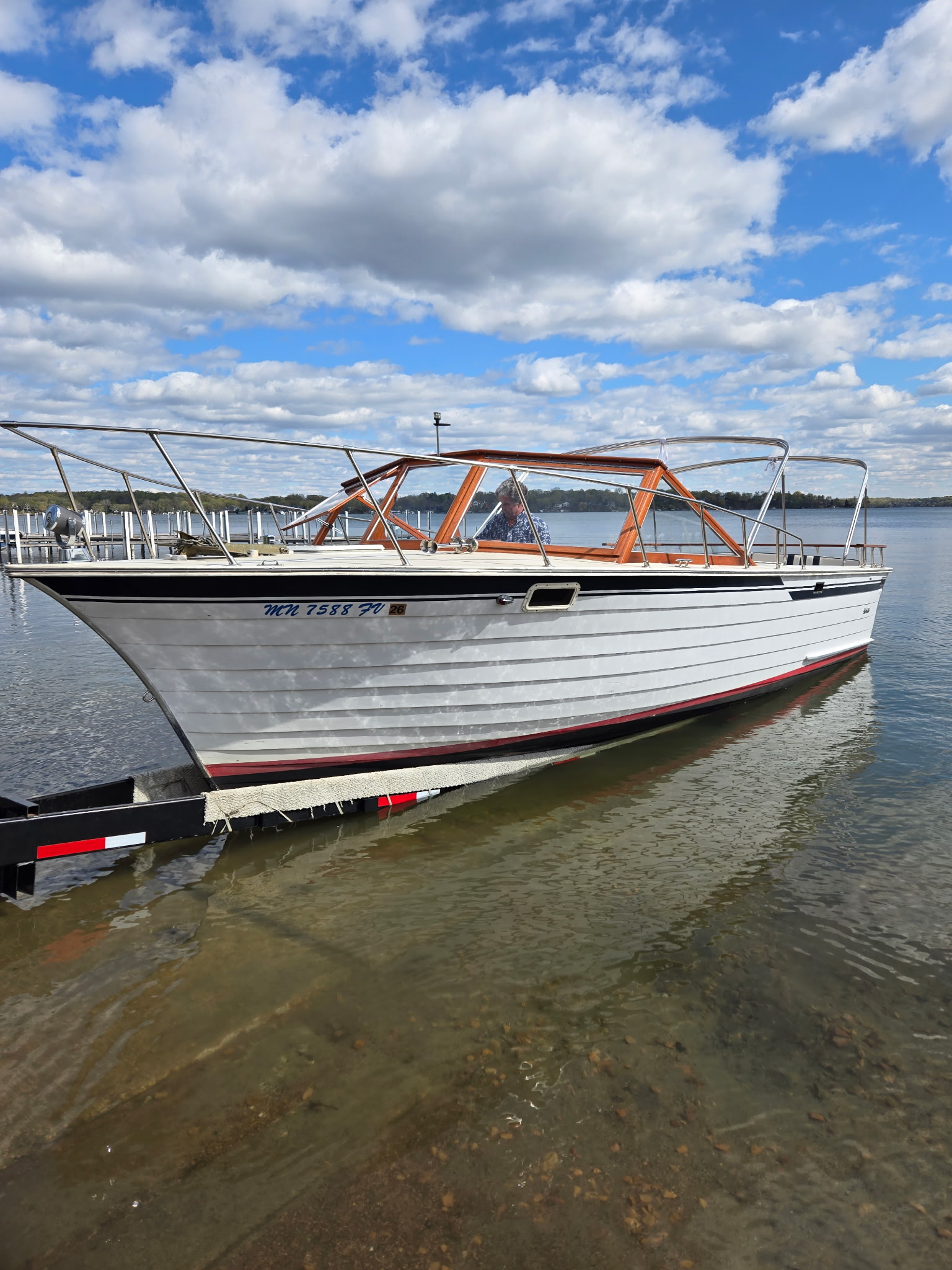 Restored classic boat being launched at a Minnesota lake ramp.
