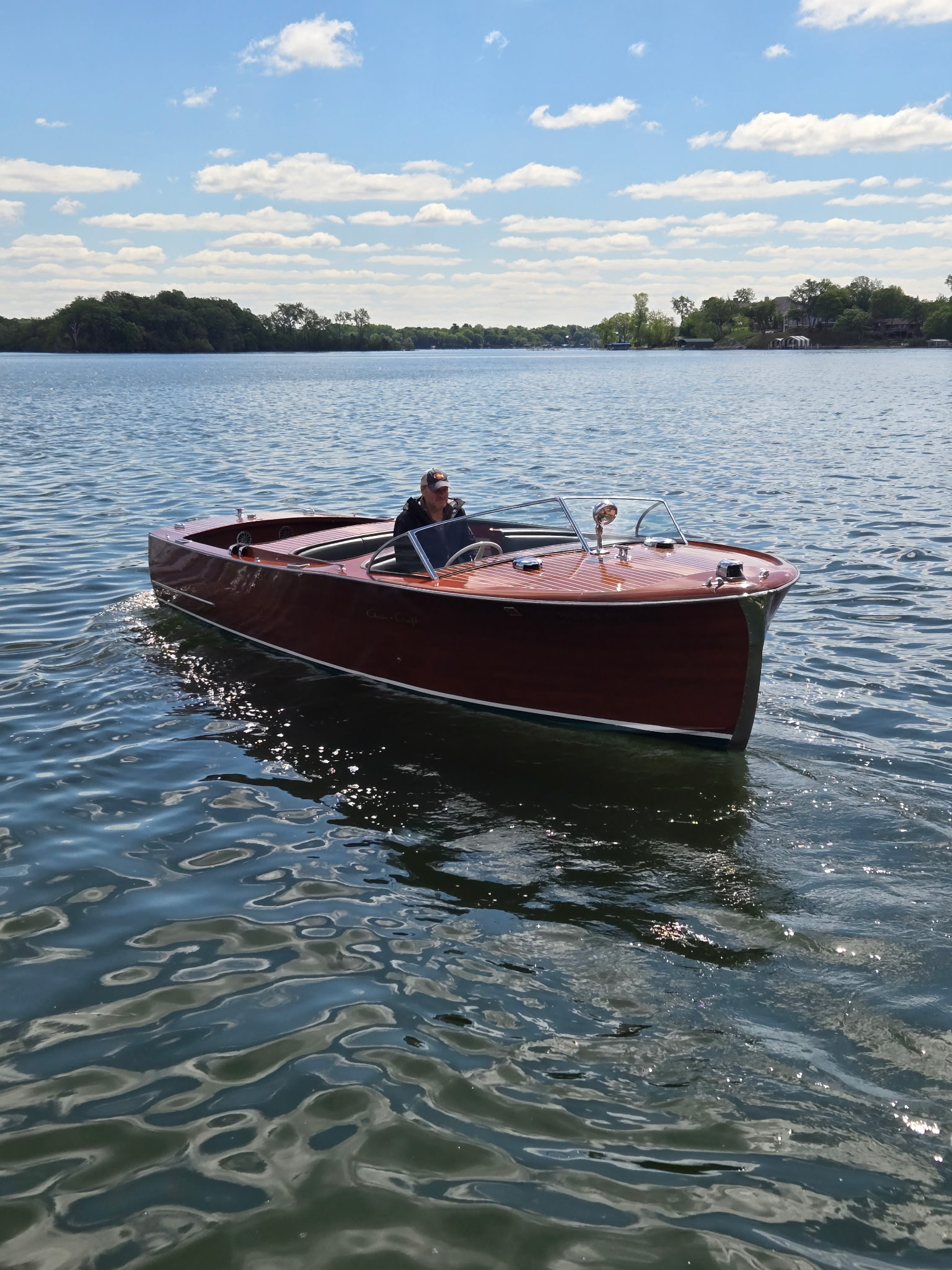 Small mahogany runabout cruising on a calm Minnesota lake.
