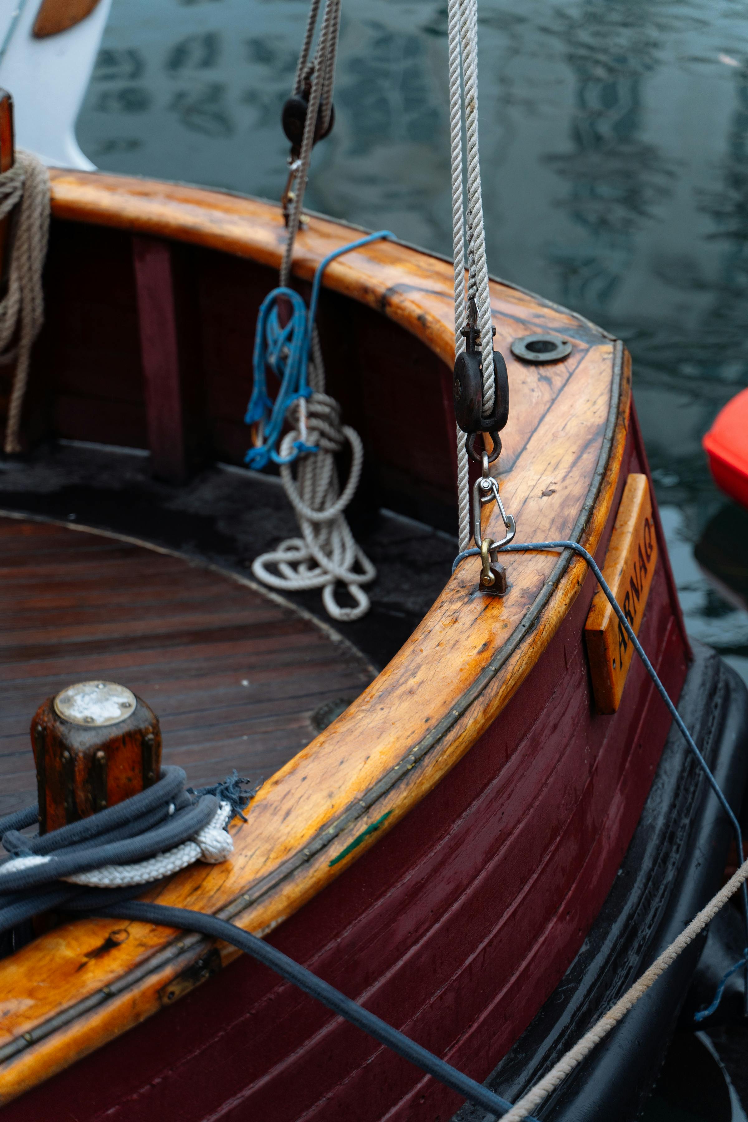 A polished mahogany bow with coiled mooring rope.