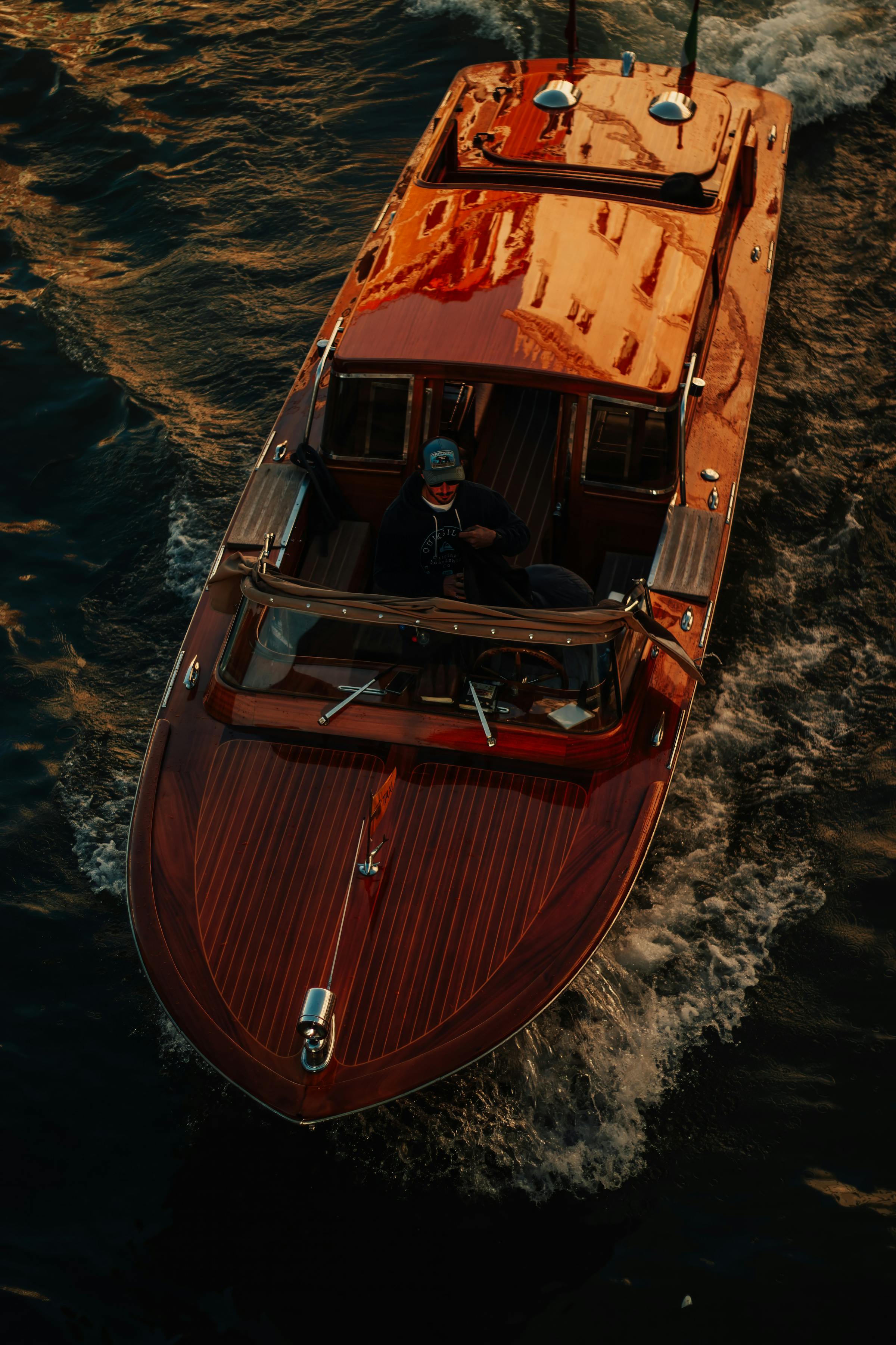A varnished mahogany Hardtop cruising on calm water at golden hour.
